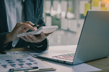 Accountant pressing calculator to make monthly financial report or company profit at desk and...