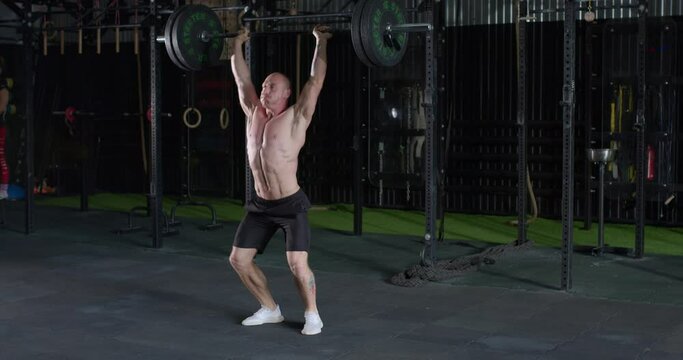 Strong muscular man doing barbell snatch exercise at gym in slow motion. lifestyle free spare time hobby motivation challenge slow motion