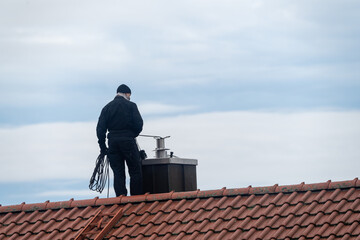 Chimney sweeper on the roof of a house in an attempt of chimney sweeping