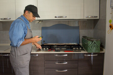 Image of a handyman technician who with a detector carries out checks in a kitchen for safety and...