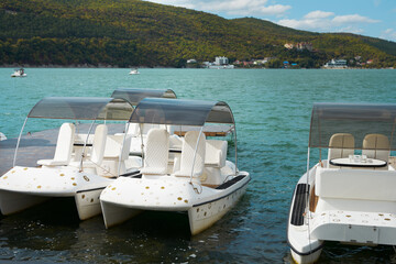 Fototapeta na wymiar Mountain lake with pleasure boats near the shore. Copy space.