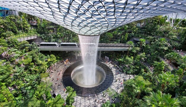 Changi Airport, Singapore - February 18, 2023 - Top view of the indoor waterfall at Jewel and the Skytrain passing the Rain Vortex into the airport terminal