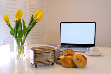 on table breakfast Yellow tulips laptop with a white screen for advertising buns a cup of coffee or...