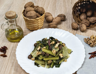 chicory catalogna with walnuts and olives on a white plate