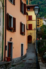 Fototapeta na wymiar Vertical shot of a narrow street with light lantern and simple buildings in Argegno, Italy