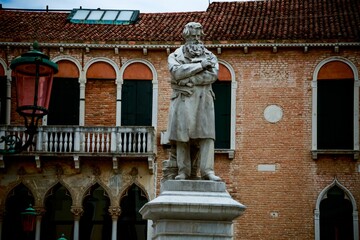 Daytime view of the statue of Niccolo Tommaseo with an old Venetian building in background, Italy