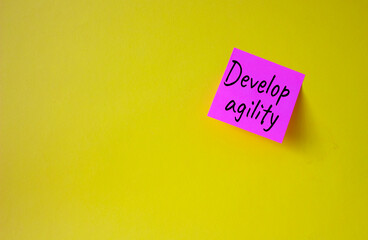 Develop agility symbol. Pink steaky note with concept words Develop Agility. Beautiful yellow background. Business and Develop agility concept. Copy space
