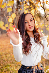 A captivating image featuring a beautiful brunette woman in the backdrop of a scenic fall park, radiating autumnal charm and natural beauty