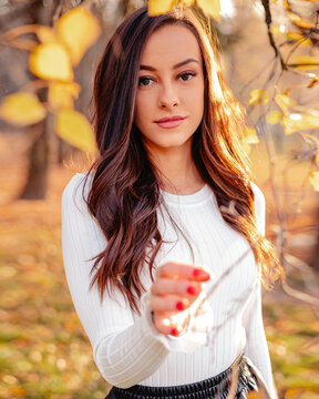 A captivating image featuring a beautiful brunette woman in the backdrop of a scenic fall park, radiating autumnal charm and natural beauty