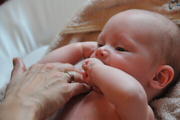 newborn child playing with mom´s  hand lying on a towel