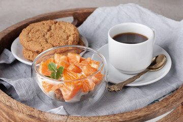 Obraz na płótnie Canvas round wooden tray with tangerine yogurt, oatmeal cookies, a cup of black coffee