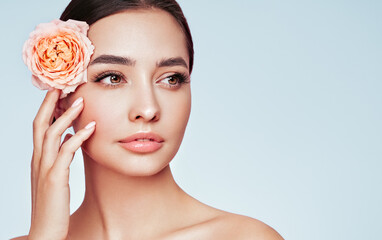 Fototapeta na wymiar Portrait beautiful young woman with clean fresh skin. Model with healthy skin, close up portrait. Cosmetology, beauty and spa. Girl with a rose flower