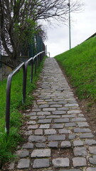 Montée ou descende des escaliers ou d'une ruelle en pierre, mal entretenu, abandonné, vers un dépôt vide et désaffûté ou rivière sale, baignade interdite ou accès réduit, sortie vers espace urbaine