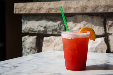 Kids non-alcoholic cocktail with ice cubes and fruit on blurred brick outdoor background