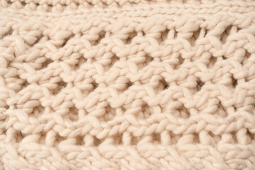 A fragment of beige knitted fabric, knitted from white sheep wool.