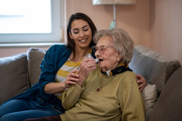Young nurse caretaker helping grandma with her inhaler. - obrazy, fototapety, plakaty