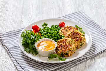 crab cakes with sauce, green peas, tomatoes