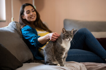 Young woman petting her cat at home.