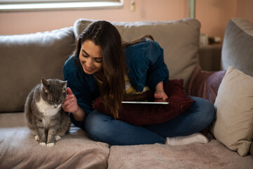 Beautiful young woman working from home, but is distracted by her cat.