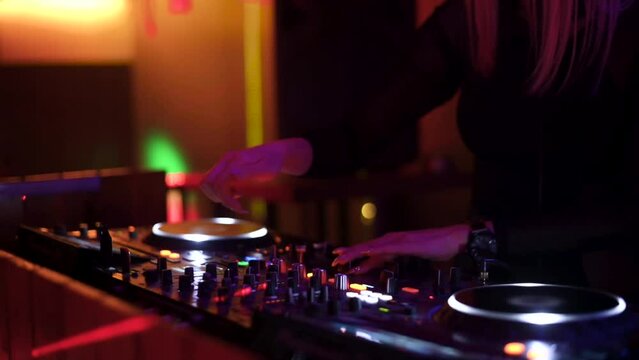 Close-Up of Dj Mixer Controller Desk in Night Club Disco Party. DJ Hands touching Buttons and Sliders Playing Electronic Music . Amazing Close Up of DJ Hands Mixing and Scratching Music on Vinyl Plate
