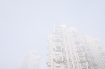 Tall residential buildings in the form of a tower, immersed in a misty sky. Cyberpunk stylistics. Dramatic, depressing mood
