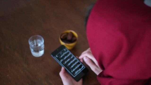 muslim woman in red hijab reads the quran on a smartphne in ramadan islam muslims with dates i water breaking the fast religion time of introspection concept modernity