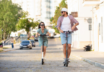 Happy young couple in love on vacation having fun, driving electric scooter through the city. Eco transport