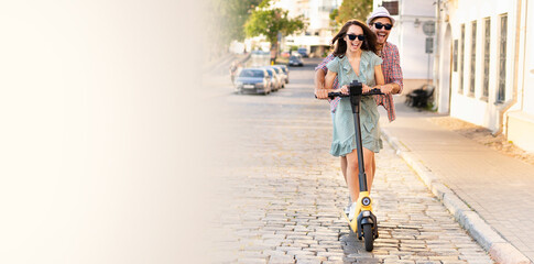 Happy young couple in love on vacation having fun, driving electric scooter through the city. Eco transport © opolja