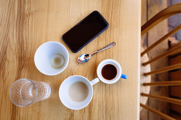 Dirty coffee cups, cappuccino and a glass of water stand on a wooden table.
