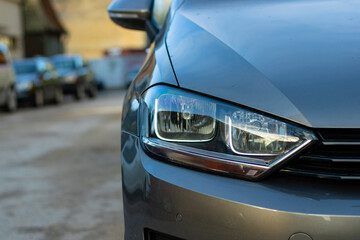 Front headlights of modern sport car black and white on city background, free space on left side...