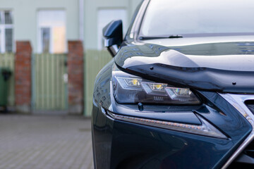 Modern car headlight close-up. Close up of new modern car headlamp. Front head light with xenon light of blue modern car on city background and fre copy space on the left.