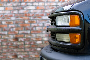 Detail on one of the LED Headlights Modern Car next to the Wall Background. Close up of Pick Up...