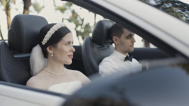 Bride and groom in wedding clothes sitting in cabriolet car. Action. Man and woman in luxury car.