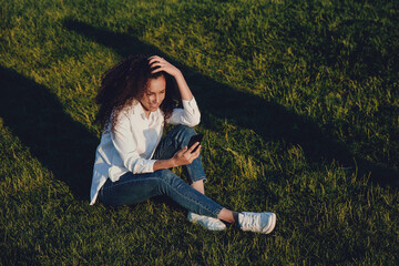 A young girl sits on the green grass.