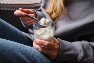 Young woman eating yogurt at home. Healthy snack
