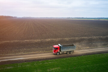 view from a drone of a dump truck moving along a field road