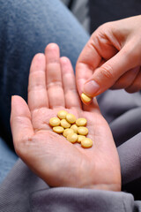 Woman pours pills or vitamins from a jar onto her hand. Taking vitamins or medications. The concept of health care, medicine, pharmacies, disease prevention. A jar with pills or vitamins in the hands
