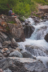 A man recording a video of a waterfall using an action camera during a hike