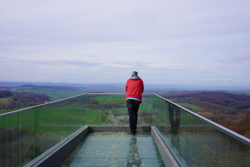 Ein Mann steht auf der Aussichtsplattform Skywalk Sonnenstein und genießt die Aussicht ins Eichsfeld in Thüringen