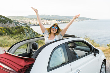 Young woman having fun in cabrio against a beach and sea - travel and summer voyage nature concept