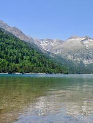 Translucent calm tranquil water of Lake Oredon in the mountains and the peak Nouvielle. Peaceful landscape of Pyrenean Mountain Range, France. Vertical photo