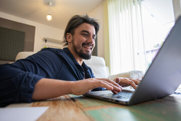Fototapeta premium Handsome young man working on a laptop at home