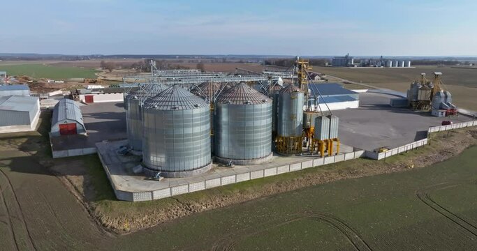 flight and aerial view over agro silos granary elevator on agro-processing manufacturing plant for processing drying cleaning and storage of agricultural products, flour, cereals and grain. 