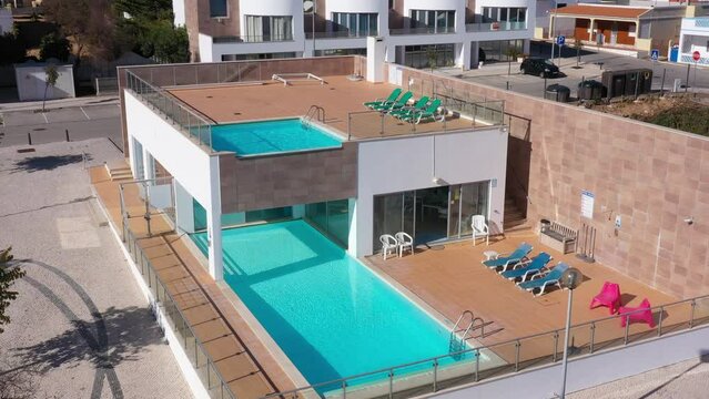 Modern swimming pool complex with sunbeds for tourists in the hotel aerial view. Portugal