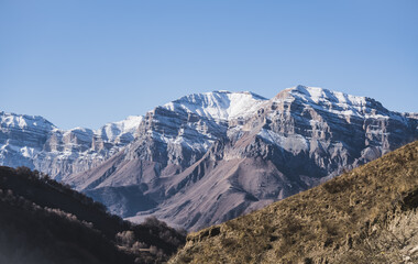 Panorama of a mountain range from layers of rocks with the first snow on the rocks and slopes, autumn mountains with the first snow