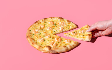 Eating shrimp pizza, minimalist on a pink background. Taking a slice of pizza