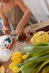 Hands of little girl paints easter eggs for holiday. Easter decoration and handmade craft as a tradition and fun. Child decorate egg. Vertical.