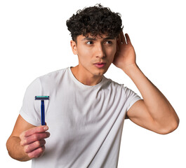 A young latin man holding a razor for shave trying to listening a gossip.