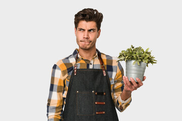 Young caucasian gardener man isolated on white background confused, feels doubtful and unsure.