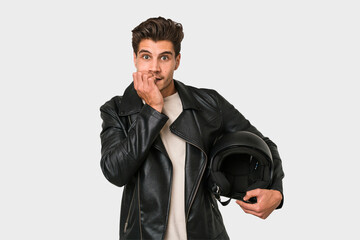 Young caucasian man holding a motrbike black helmet isolated biting fingernails, nervous and very anxious.